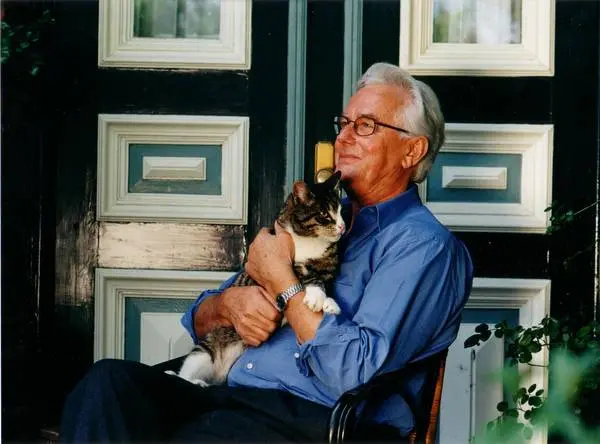 Alter Mann mit Katze auf dem Arm sitzt auf einem Stuhl 